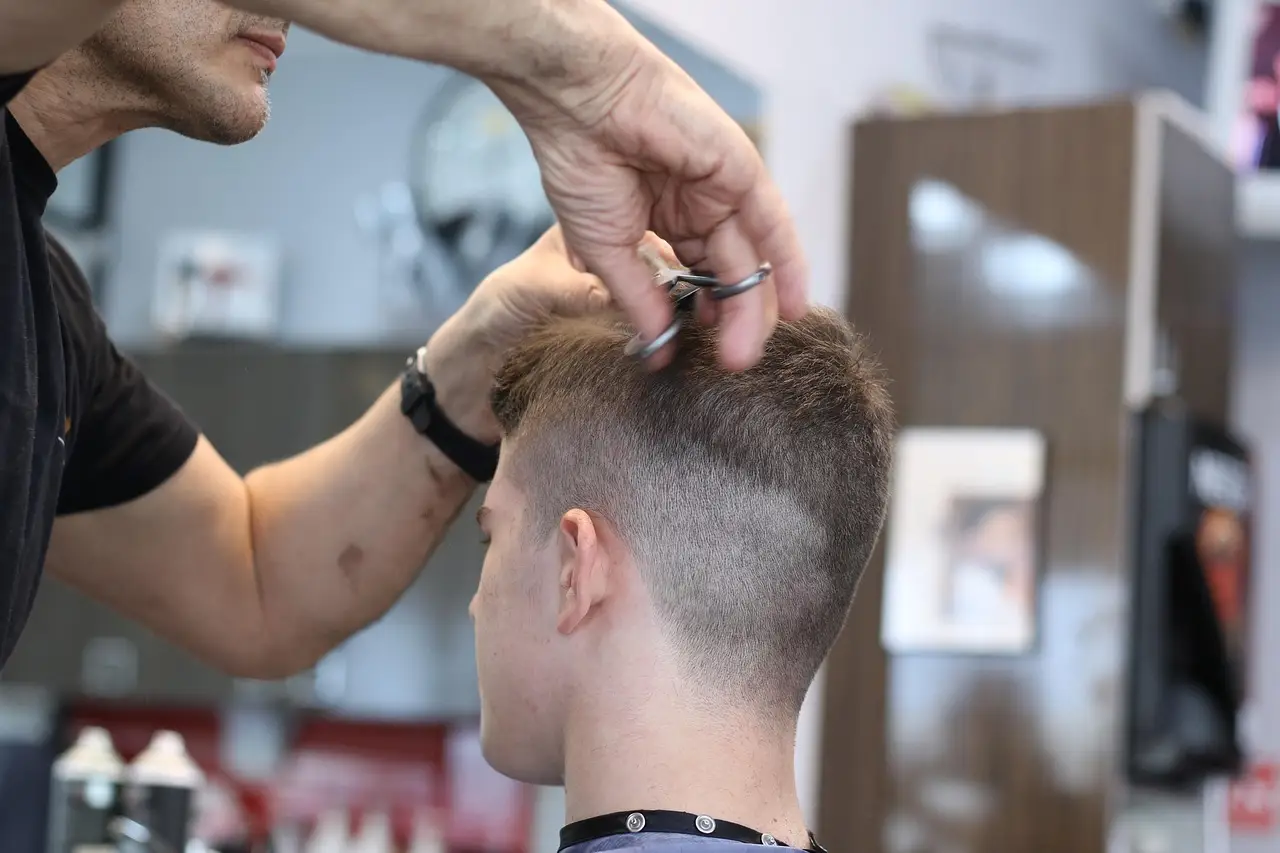 A barber cutting a sharp fade with scissors and comb