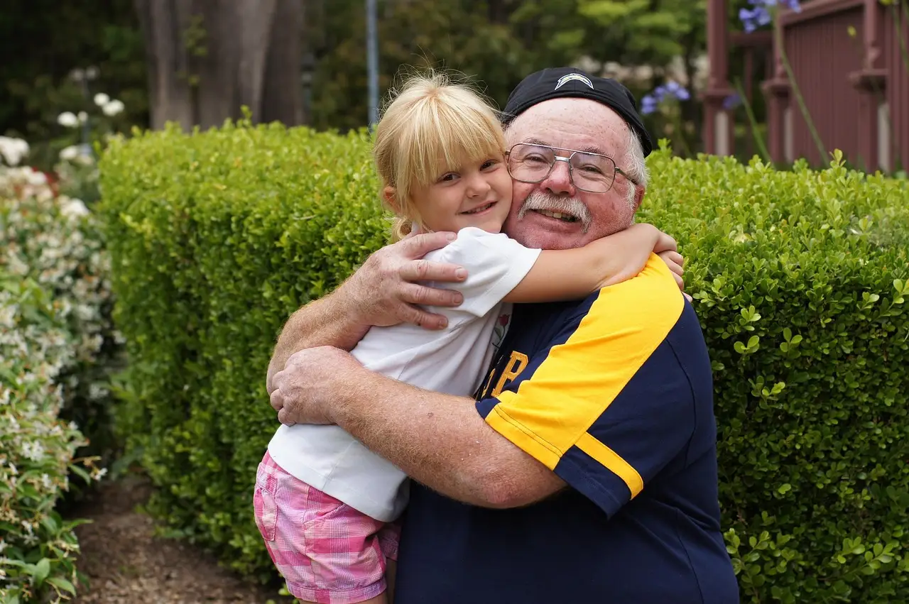 A grandfather hugging his granddaughter outside