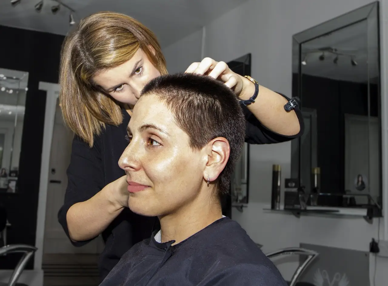 A stylist cutting a woman’s short hair in a salon